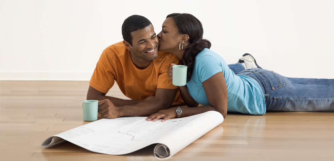 Couple looking at blueprints on floor of new home