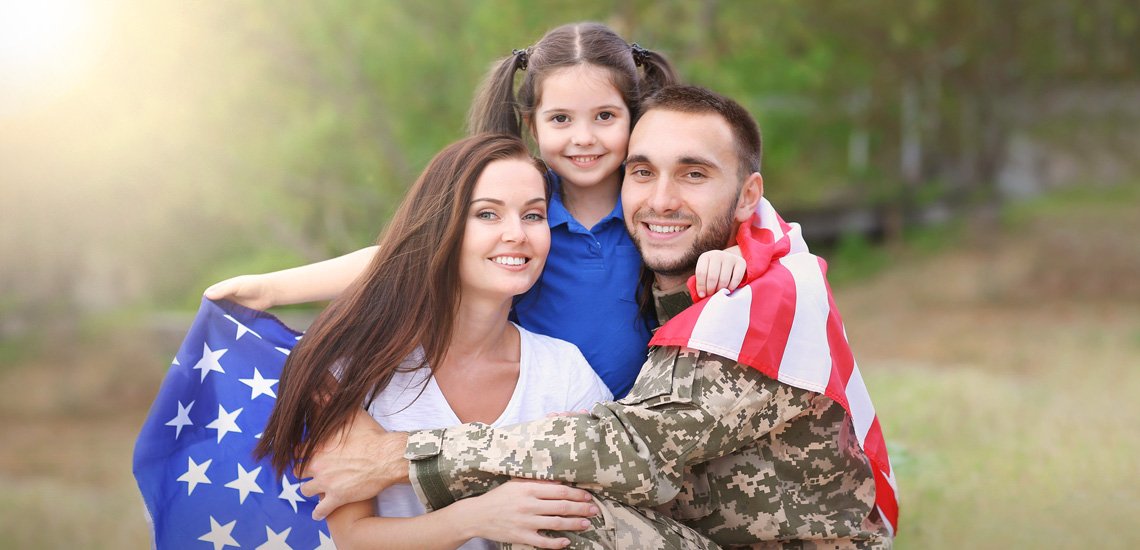Veteran holding family close while wrapped around American flag